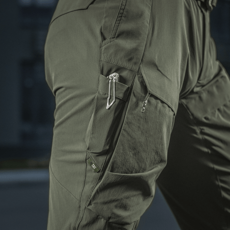 Yksityiskohta M-Tac Rubicon Flex -housuista innovatiivisella cargo-taskusuunnittelulla, sopii ulkoaktiviteetteihin ja treeniin.