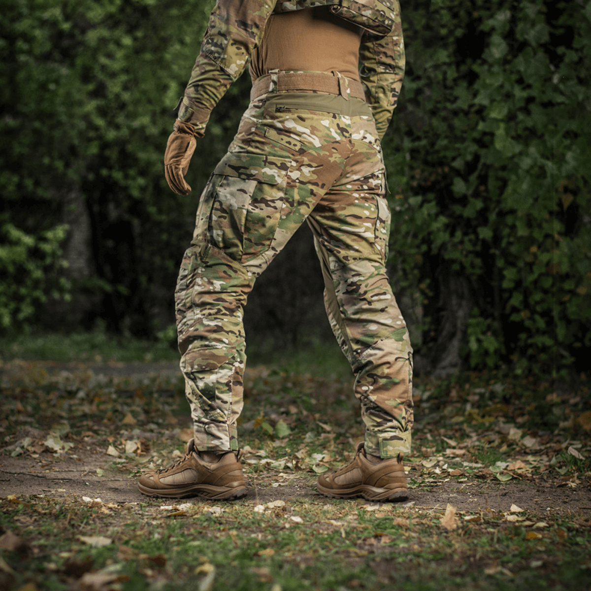 Henkilö pukeutuneena M-Tac-housuihin STURM NyCo Extreme Gen.II maastokuosissa metsäympäristössä.