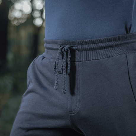 Henkilö pukeutuneena M-Tac Stealth Cotton -housuihin kuminauhalla vyötäröllä ja sivutaskuilla, valmistettu 100% puuvillasta mukavuuteen ja liikkumisvapauteen.