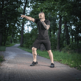 Mies metsässä M-Tac Shorts Casual Fit Cotton -shortseissa, näyttää liikkuvuuden ja pelkistetyn muotoilun puupolulla.