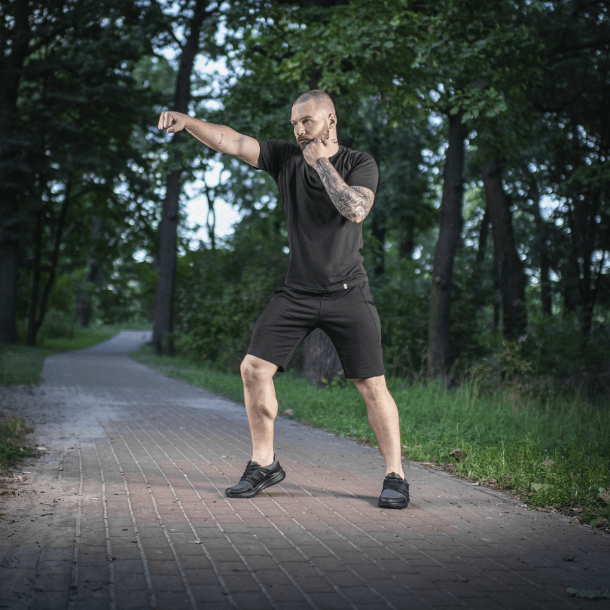 Mies metsässä M-Tac Shorts Casual Fit Cotton -shortseissa, näyttää liikkuvuuden ja pelkistetyn muotoilun puupolulla.
