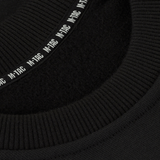 Yksityiskohta M-Tac Sweatshirt Cotton Hardista näyttää resorin ja heijastavan logon mustassa 100% puuvillamateriaalissa, tiheys 390 g/m².