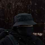 Henkilö pukeutuneena M-Tac Panama Rip-Stop army-hattuun puolijäykällä lipalla ja tuuletuksella. Suunniteltu maastokuviointiin ja tuulen suojaukseen.