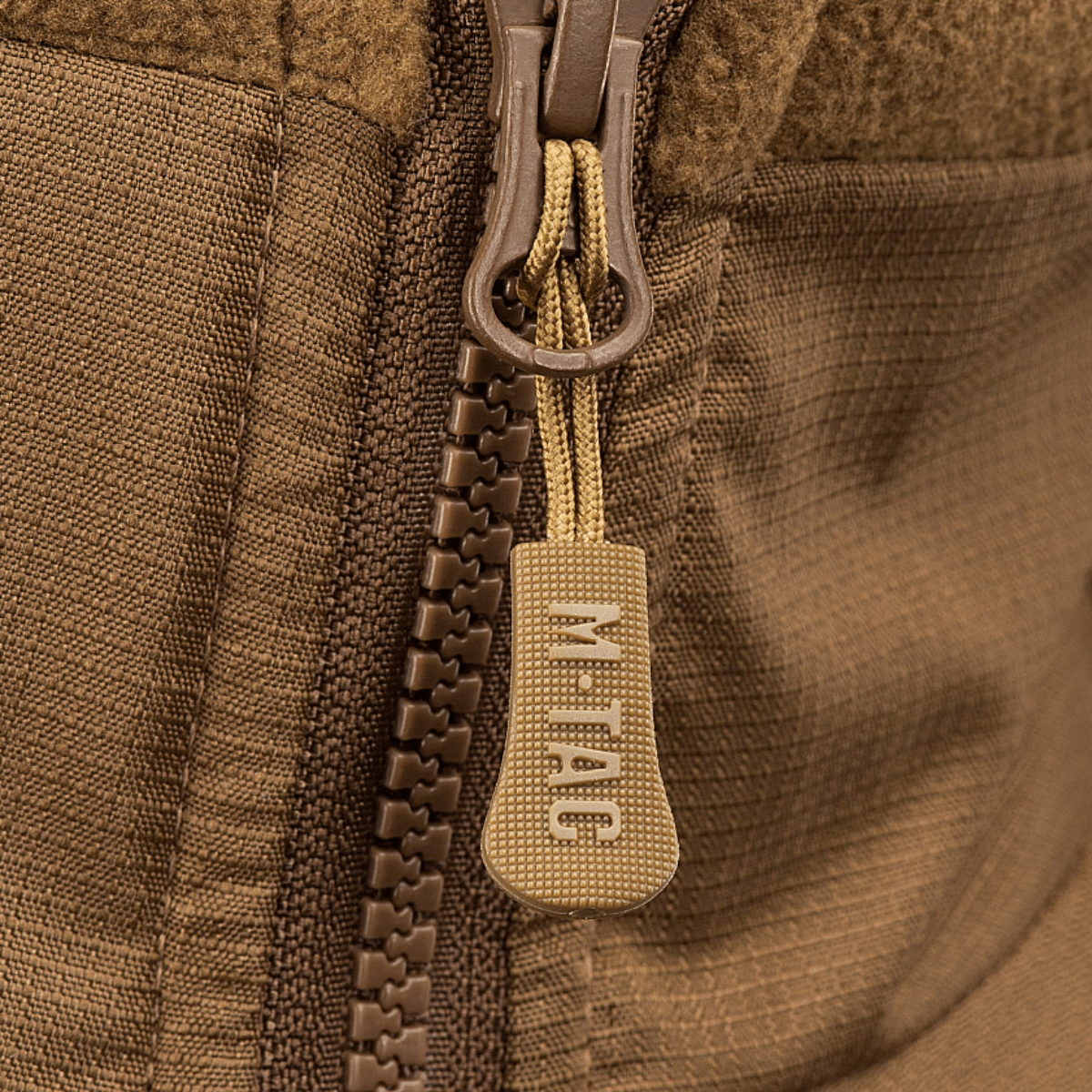 Vetoketjun yksityiskohta M-Tac Alpha Microfleece takki Gen.II:stä, tehty vahvistetusta fleecestä ja Oxford-nylonista taktiseen käyttöön.