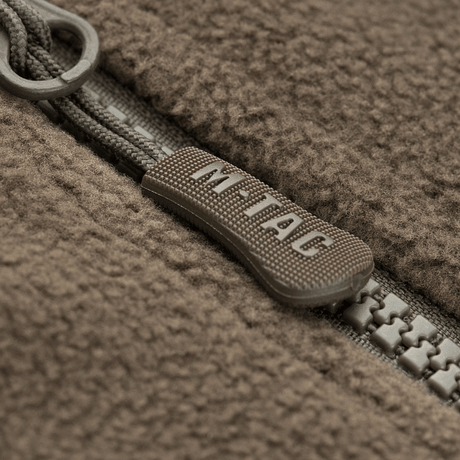 Lähikuva vetoketjusta M-Tac Alpha Microfleece takki Gen.II:stä, näyttää kulutuskestävän rakenteen ja fleece-kankaan yksityiskohdat.