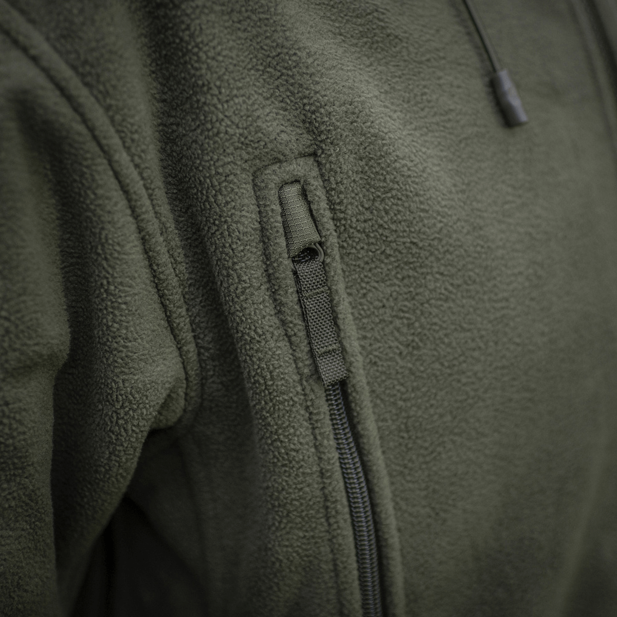 Lähikuva M-Tac Division Gen.II Windblock fleecetakista vetoketjutaskulla ja vihreällä fleece-kankaalla.