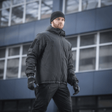 Mies pukeutuneena M-Tac Alpha Gen.III Pro talvitakkiin, suunnattu mukavuuteen ja toimivuuteen kylmässä säässä, sopii lämpötiloihin jopa -20°C.