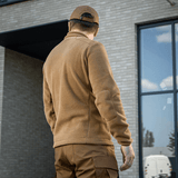 Mies M-Tac Nord Polartec -fleecetakissa ruskeana rakennuksen edessä.