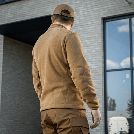 Mies M-Tac Nord Polartec -fleecetakissa ruskeana rakennuksen edessä.