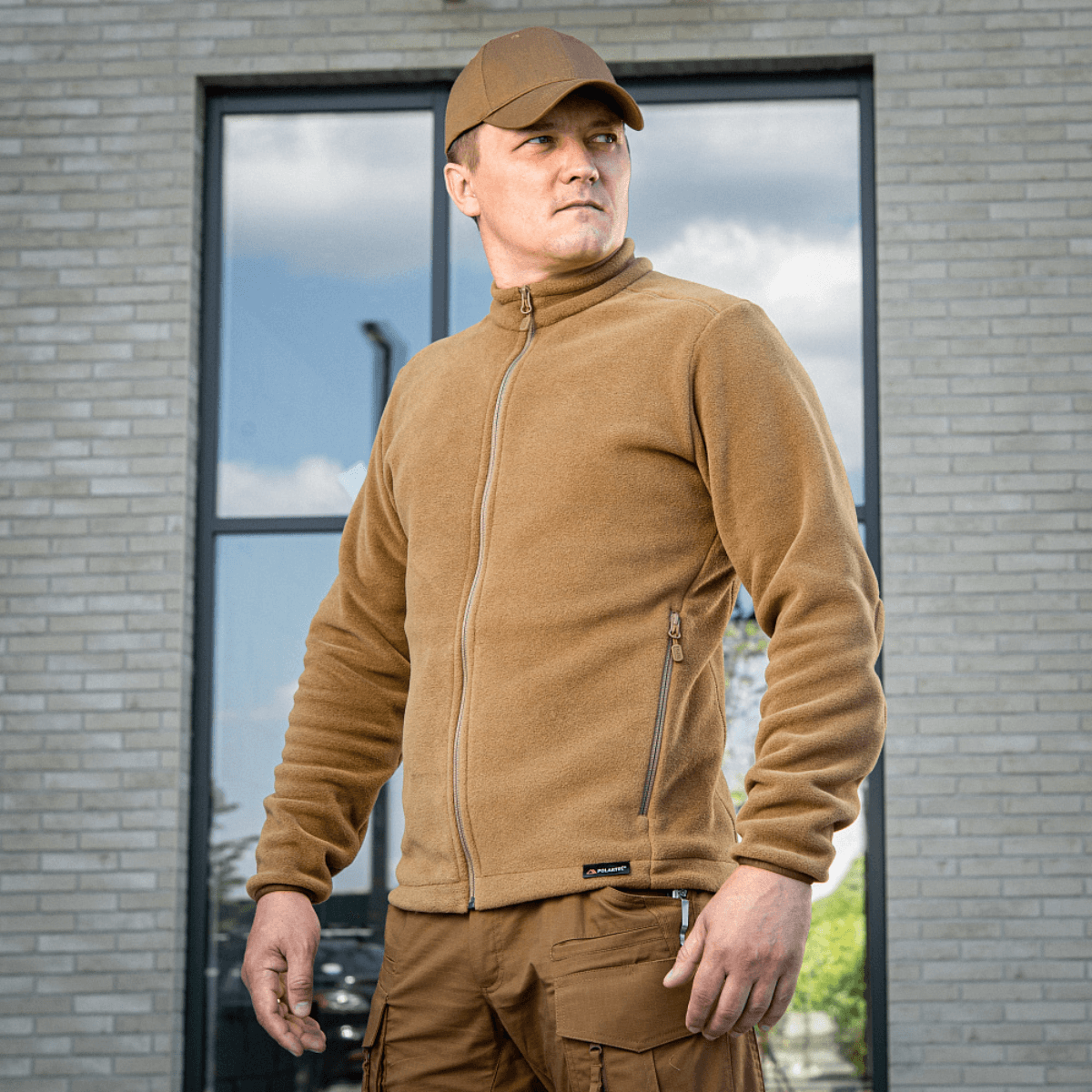 Mies M-Tac Nord Polartec -fleecetakissa beigeenä, sopii arkeen ja urheiluun, ulkona modernin taustan kanssa.