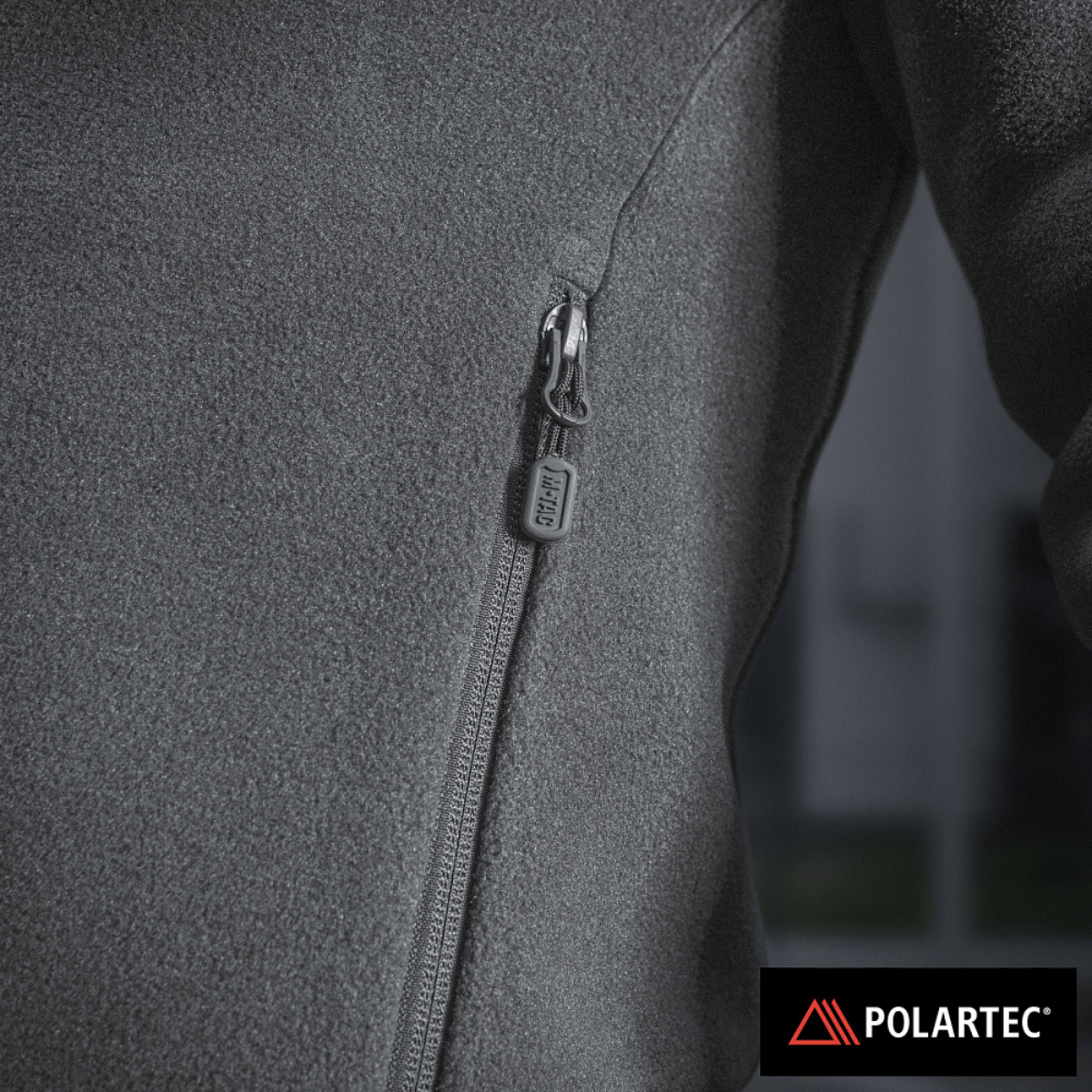 Lähikuva vetoketjun yksityiskohdasta ja Polartec®-logosta, valmistettu premium-lämmöneristävästä materiaalista.
