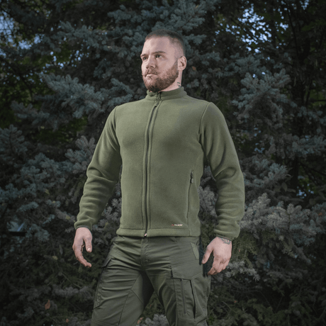 Mies pukeutuneena M-Tac Nord Polartec -fleecetakkiin metsätaustan edessä, näyttää takin käytön ulkona.