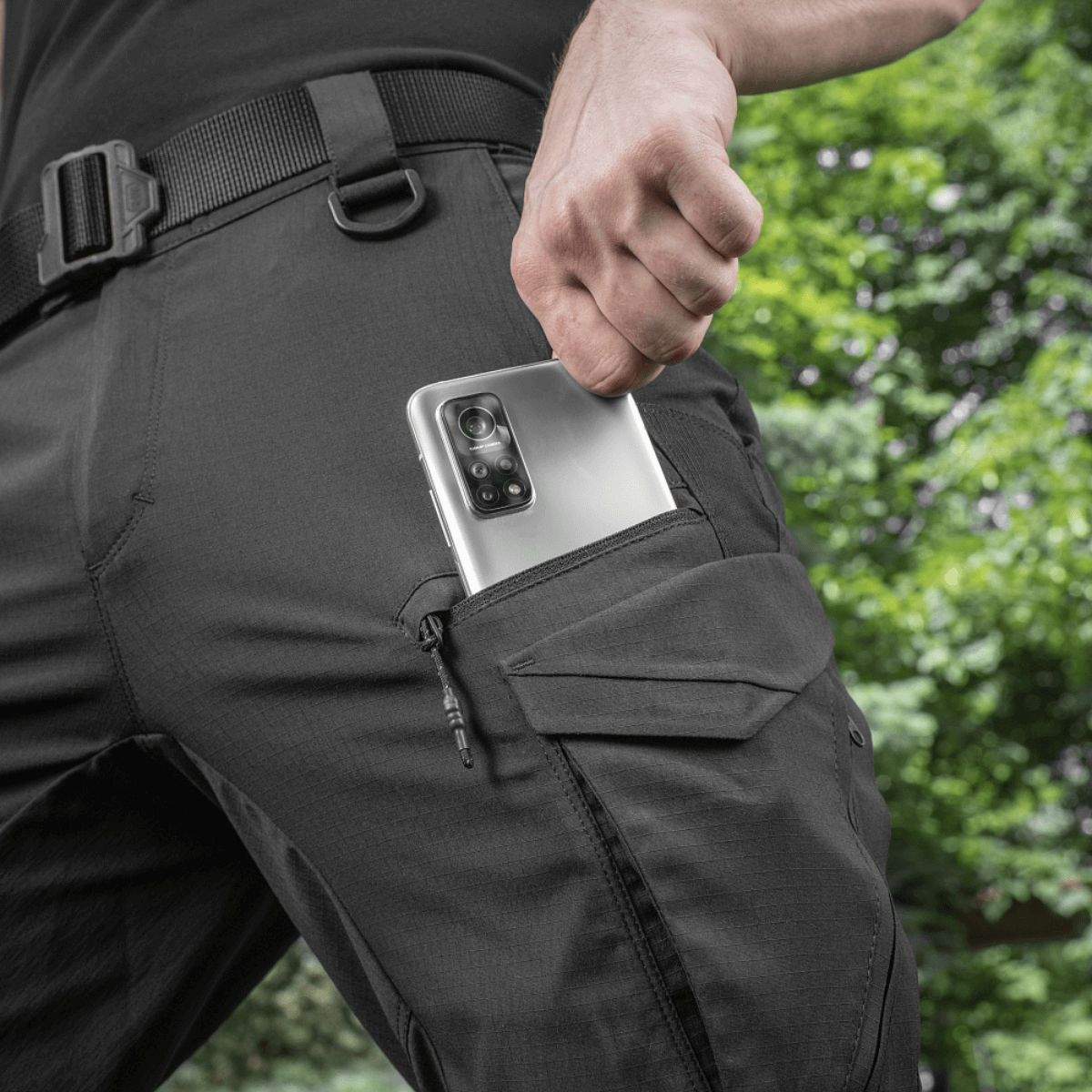 M-Tac Aggressor Summer Flex Shorts taskulla ja puhelimella mustana, kevyt ja hengittävä Flex Rip-Stop -kangas, täydellinen ulkokäyttöön.