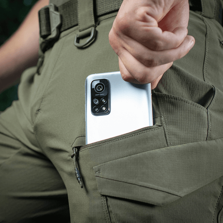 M-Tac Aggressor Summer Flex Shorts, puhelin taskussa, elastinen vyötärö ja taktinen muotoilu.