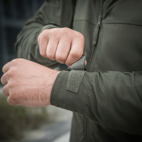 Henkilö säätää M-Tac Flash -takin hihaa, kevyt takki vaellukseen ja arkeen, helppo yhdistää tavallisiin vaatteisiin.