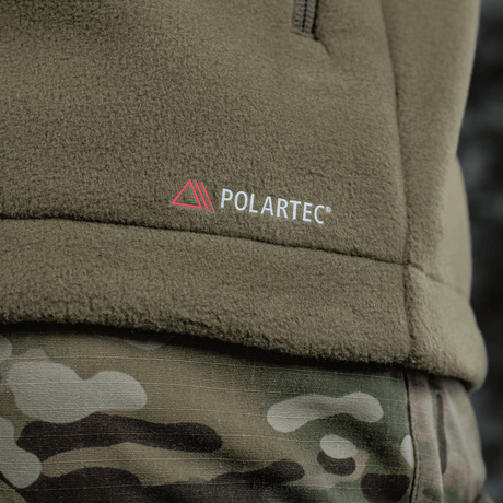 M-Tac Combat Fleece Polartec -takki Polartec®-logolla, lähikuva takista ja maastohousuista taktiseen ilmeeseen.