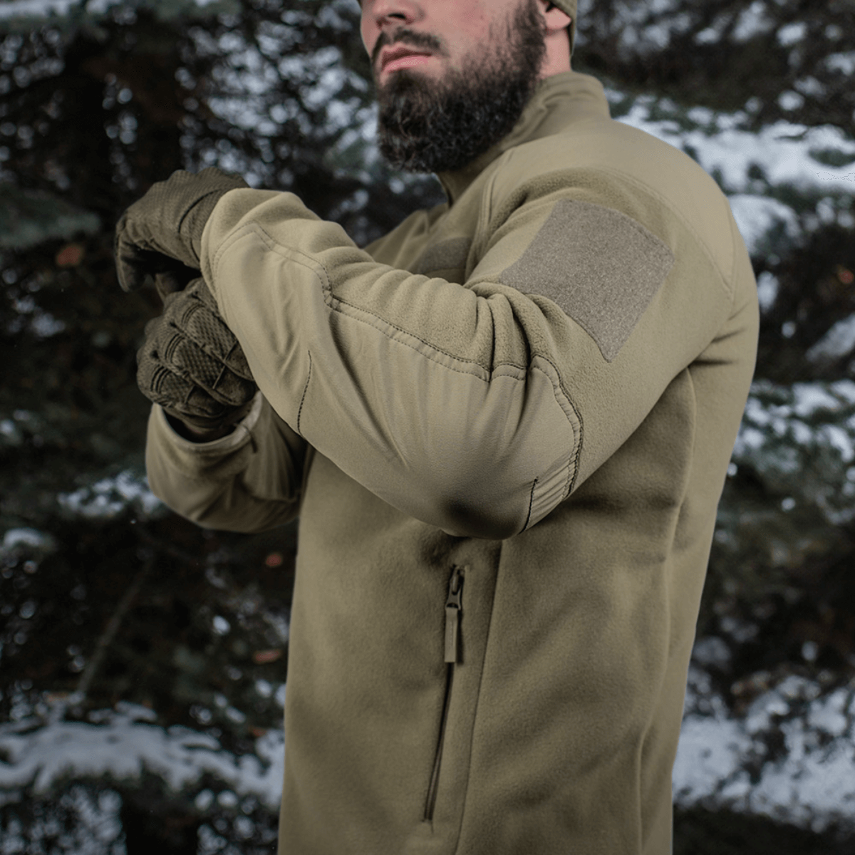 Mies metsässä pukeutuneena M-Tac Combat Fleece Polartec -takkiin, korostaa taktista muotoilua.