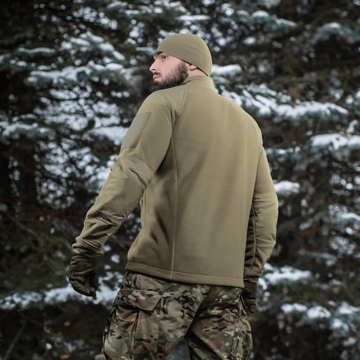 Henkilö metsässä pukeutuneena M-Tac Combat Fleece Polartec -takkiin, takaa kuvattuna. Sopii taktiseen ja arkipukeutumiseen.