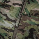 Yksityiskohtainen lähikuva vetoketjusta ja kankaasta M-Tac Alpha Gen.IV Pro Primaloft -takissa alkuperäisellä Multicam-kuviolla.