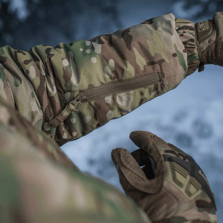 Yksityiskohta M-Tac Alpha Gen.IV Pro Primaloft -takista Multicam-kuosissa, näyttää vetoketjutaskun ja vettähylkivän materiaalin.