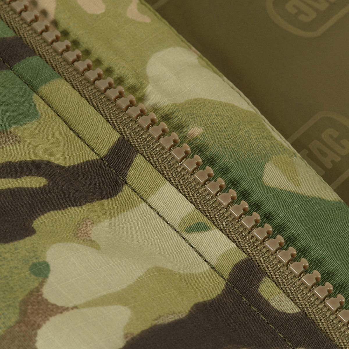 Yksityiskohta M-Tac Alpha Gen.IV Pro Primaloft -talvitakista Multicam-kankaalla ja vetoketjulla.