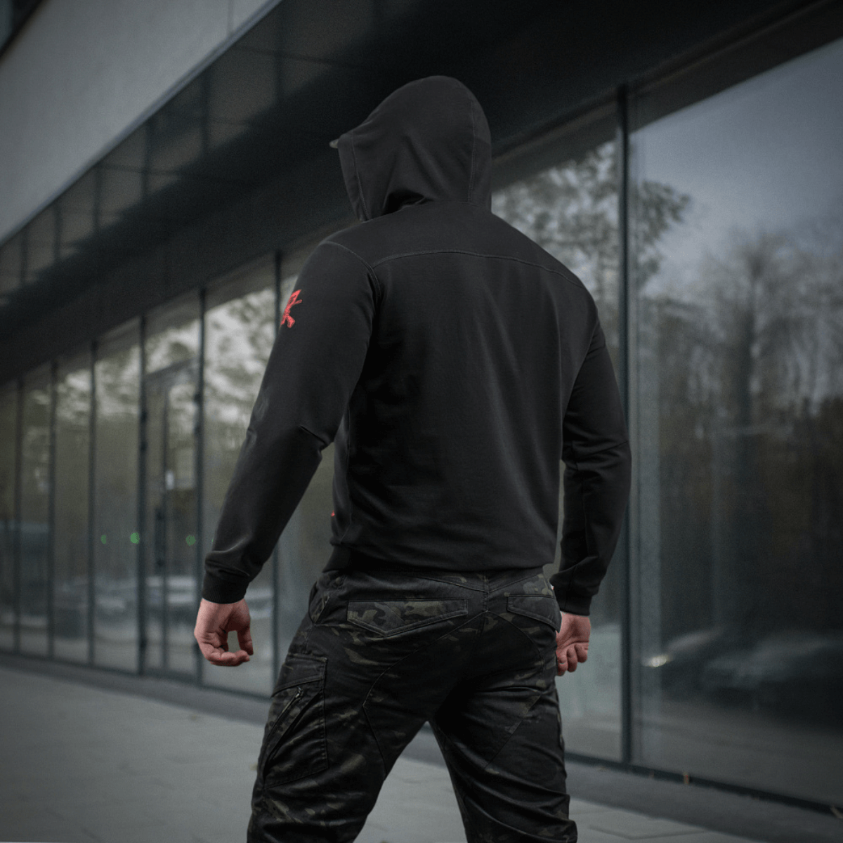 M-Tac Hoodie Freedom nähtynä takaa urbaanissa ympäristössä, näyttää hupun ja istuvuuden, sopii arkeen ja aktiiviseen ulkoiluun.