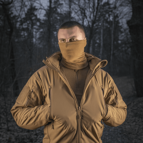 Mies metsässä käyttäen M-Tac Tube Scarf Polartec -kauluria, suojaa tuulelta ja kylmyydeltä, sopii outdoor-aktiviteetteihin kylminä vuodenaikoina.