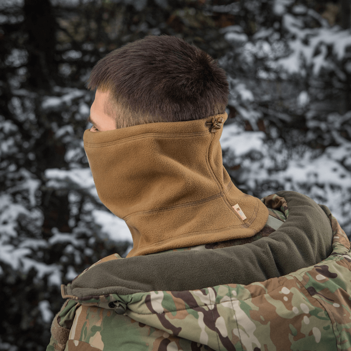 Henkilö käyttää M-Tac Anatomisk Snood Justerbar Elite Fleece (320 g/m²) luonnossa, suunniteltu suojaamaan kylmältä ja tuulelta.