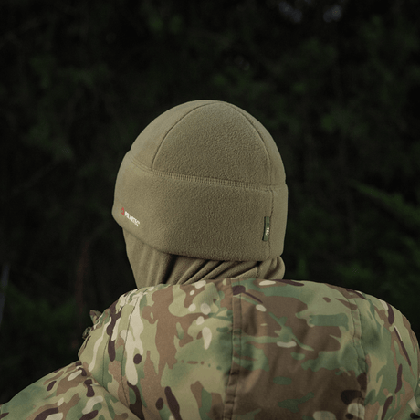 Henkilö, jolla on M-Tac Fleece Polartec Watch Cap ja naamiointikuosinen takki metsässä