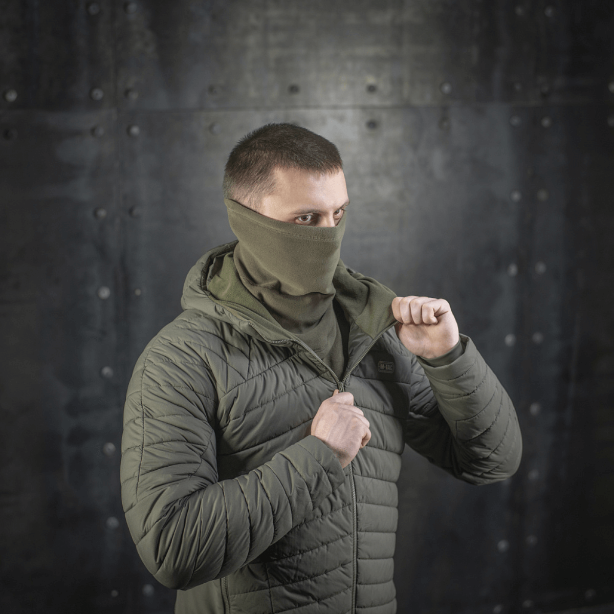 Miehellä on M-Tac Polartec Anatomic Tube Scarf kasvomaskina, suojaa kylmältä ja tuulelta. Kestävä Polartec®-fleecemateriaali, ihanteellinen ulkokäyttöön.