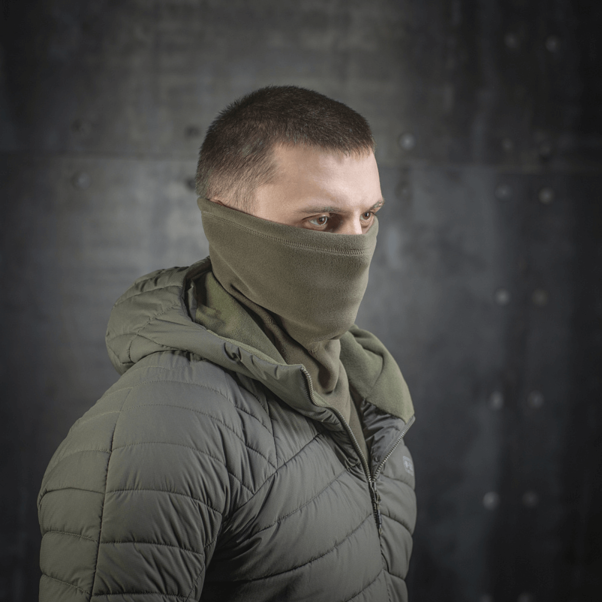 M-Tac Polartec Anatomic Tube Scarf käytettynä kasvomaskina metallitaustaisessa ympäristössä, näyttää monipuolisuutta ja tyyliä.