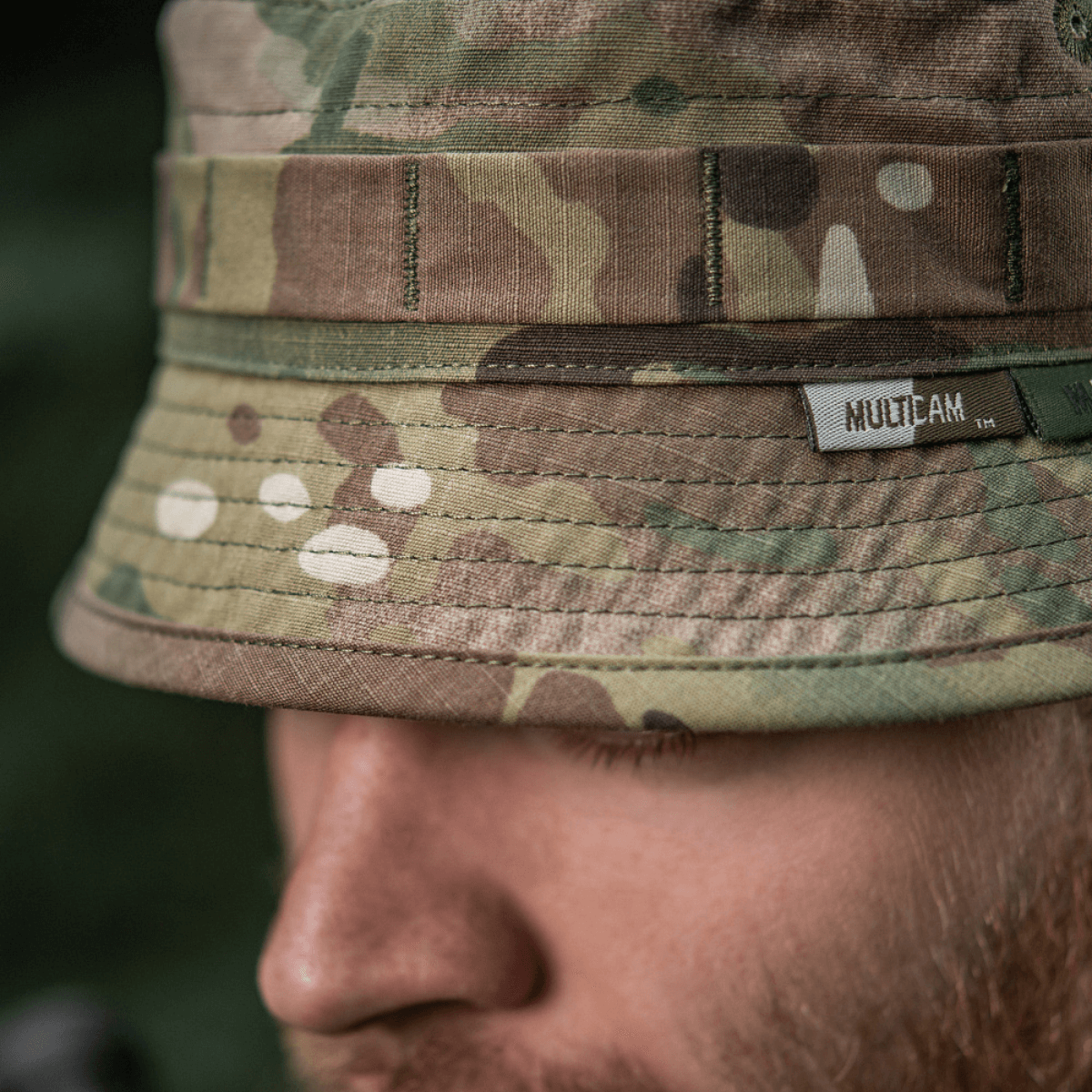 Lähikuva M-Tac Panama Hat Gen.II NYCO:sta, camo-kuvio, esittelee kestävää NYCO-kangasta ja MOLLE-liitäntää, päällä henkilö ulkona.