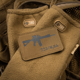 M-Tac AR-15 223/5,56 Laser Cut Patch, kiinnitetty ruskeaan taktiseen peitteeseen M-Tac-logolla, suunniteltu ulko- ja sotilaskäyttöön.