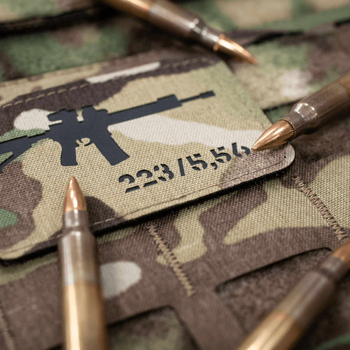 M-Tac AR-15 223/5,56 Laser Cut Patch, sijoitettu maastokuvioon ammusten kanssa, Velcro-takapuoli, Cordura 500D, taktinen ja kestävä ulkokäyttöön.