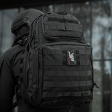 M-Tac Patch Bad Boy (kirjonta) kiinnitetty mustaan taktiseen reppuun, en, näyttää ace of spades -kuvion koiran kallolla.