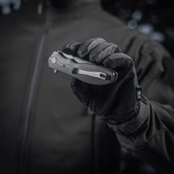 Henkilö käsineessä pitelee M-Tac Outdoor & Militær Type 6 -taittoveistä, musta G10-komposiittikahva.