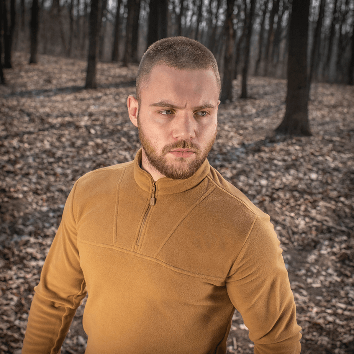 Mies pukeutuneena M-Tac Delta Polartec fleece-takkiin metsässä, näyttää siistin ja toiminnallisen muotoilun, sopii kylmiin päiviin.