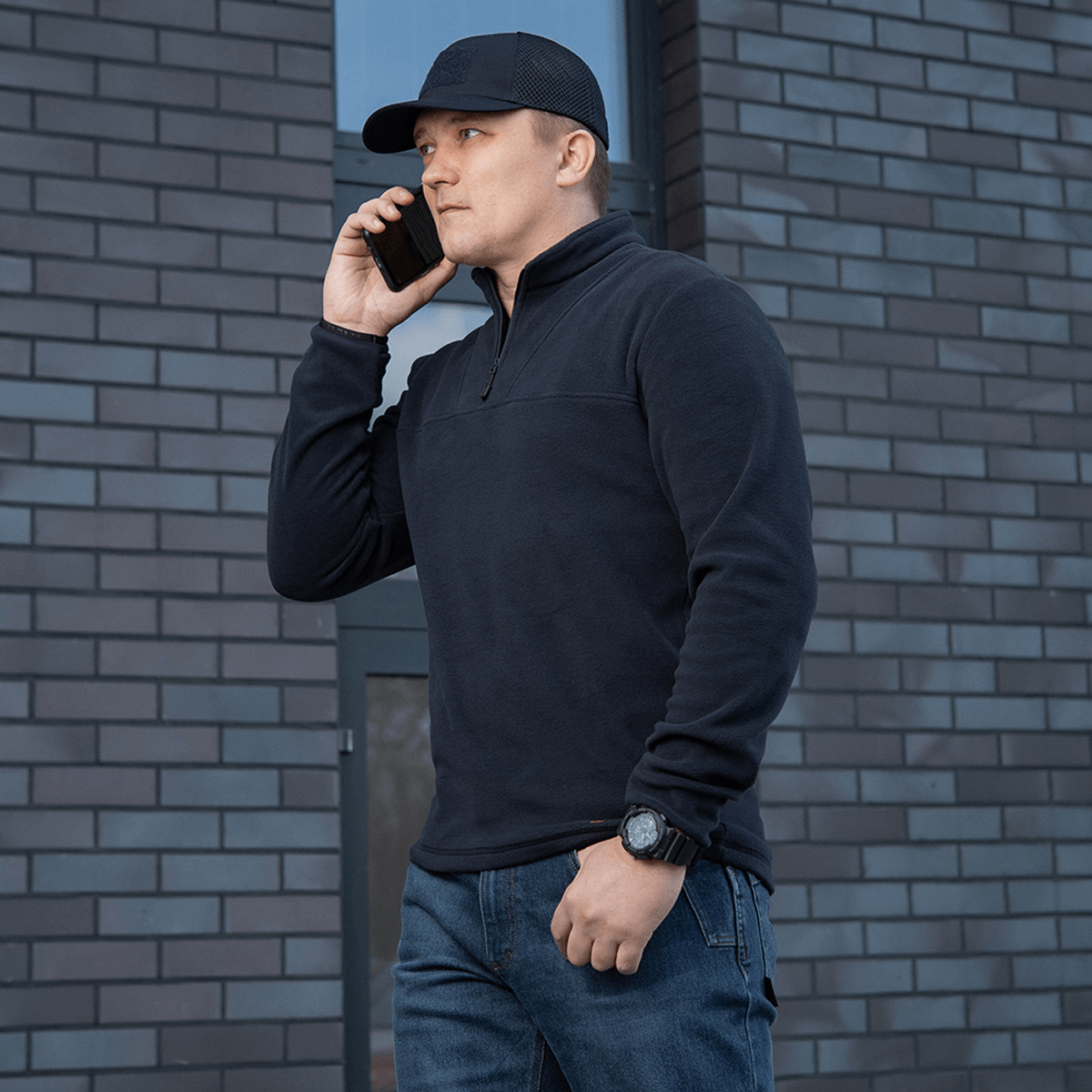Mies käyttää mustaa M-Tac Delta Polartec -fleece-takkia, puolivetoketjulla.
