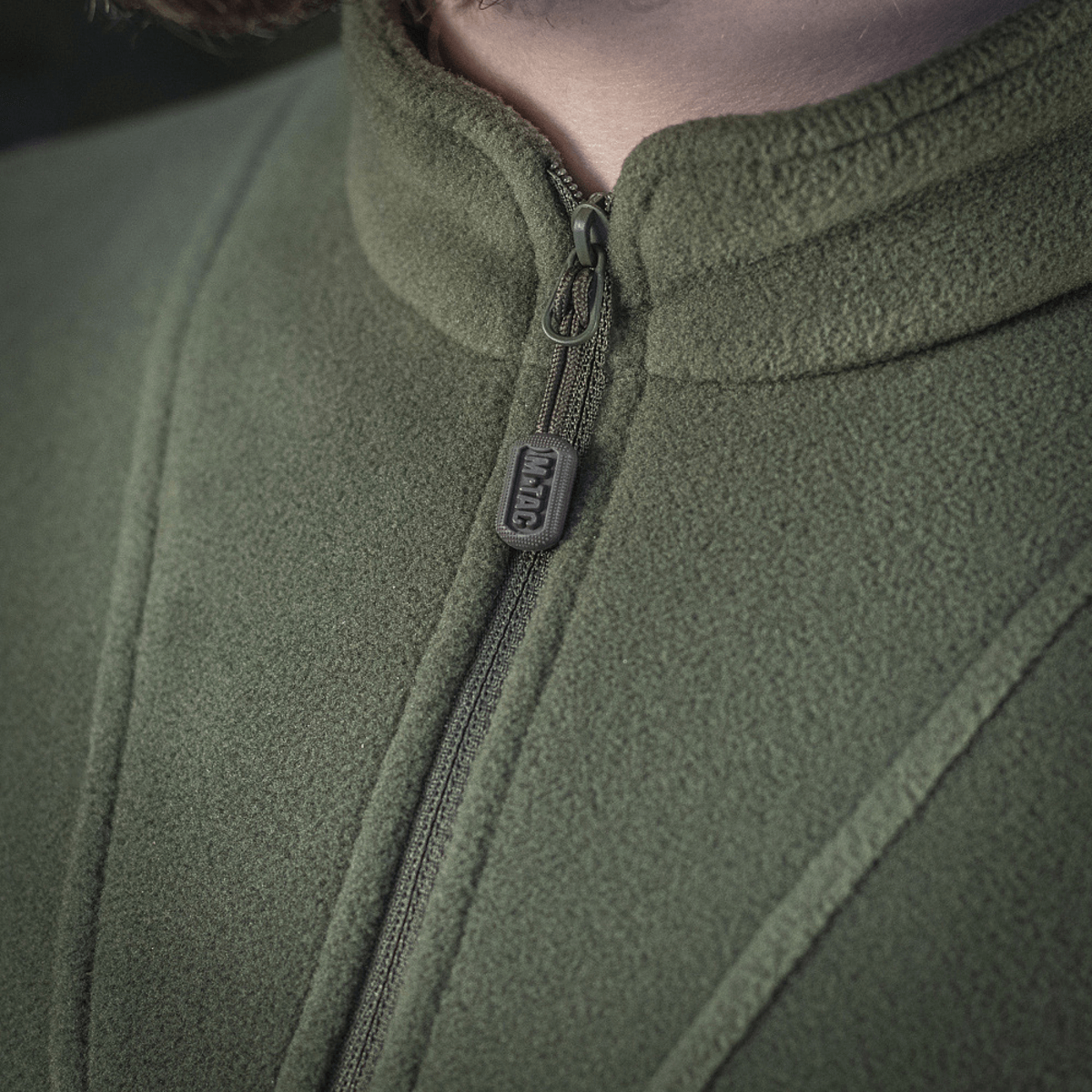 Lähikuva M-Tac Delta Polartec fleece-takista vihreänä, näyttää vetoketjen ja kangasrakenteen yksityiskohtia, valmistettu Polartec® Micro Series -fleecestä.