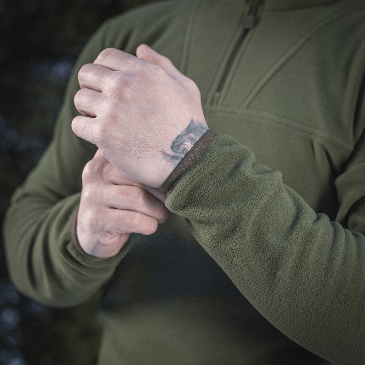 Henkilö pukeutuneena M-Tac Delta Polartec fleece-takkiin säätää hihaa ulkoilmassa.