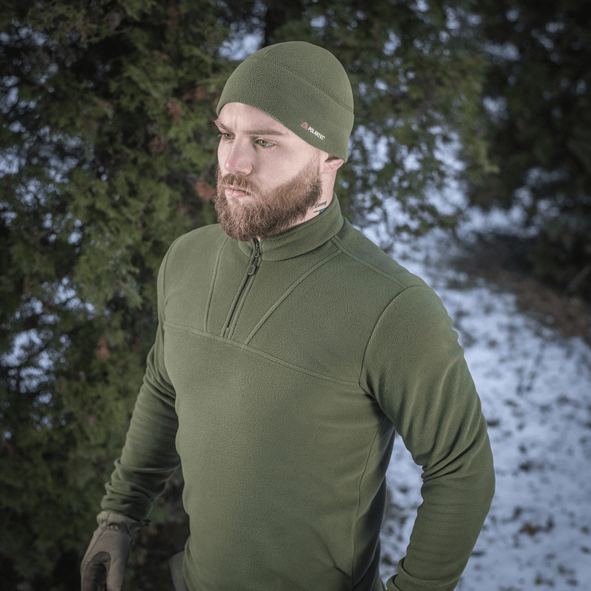 Mies pukeutuneena M-Tac Delta Polartec fleece-takki, metsä ja lumi taustalla, tyylikäs ja käytännöllinen kylmiin päiviin.