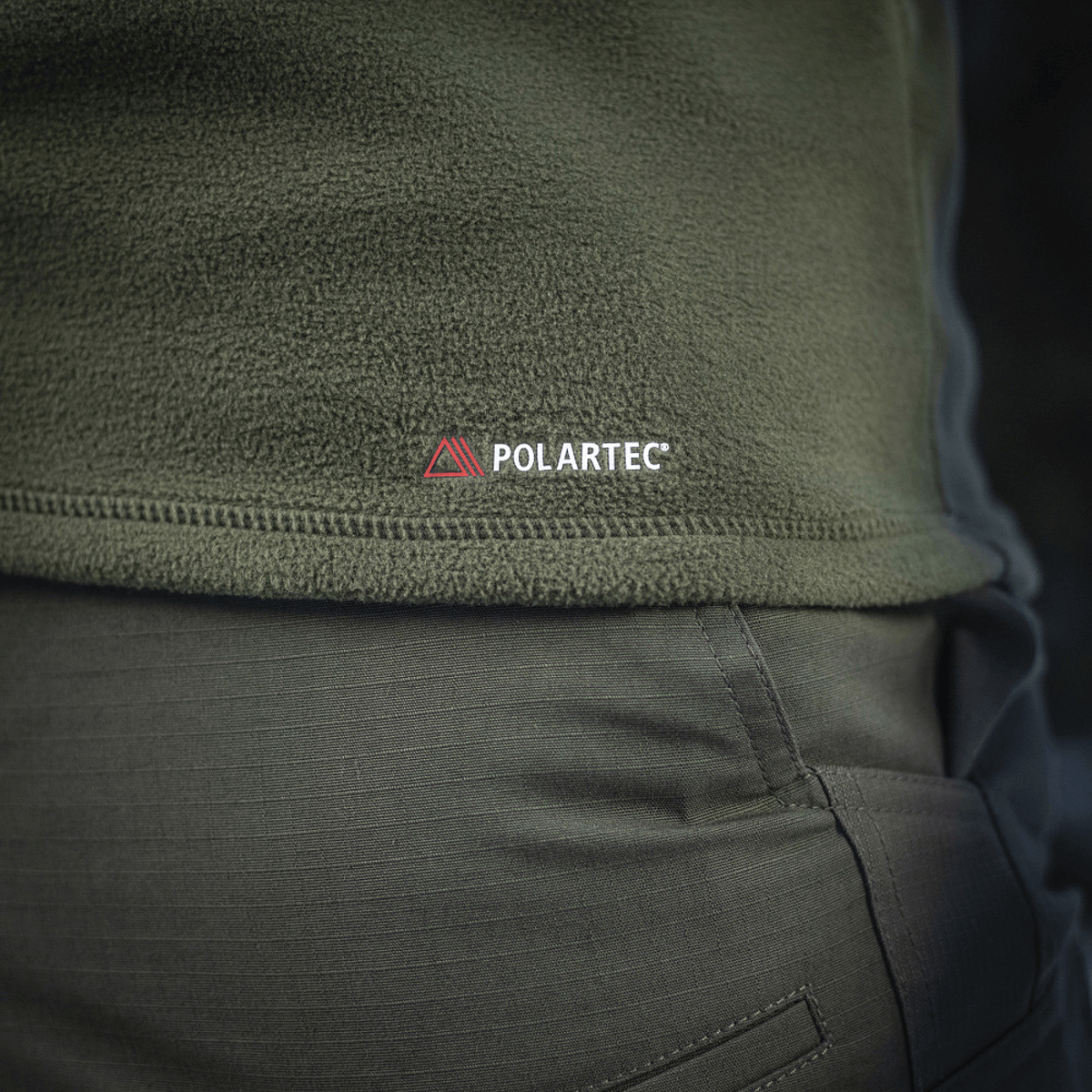 Lähikuva M-Tac Delta Polartec fleece-takista oliivinvihreänä, näkyy Polartec-logo ja kestävä, hengittävä Polartec® Micro Series -fleece.