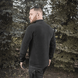 Mies M-Tac Polartec Sport -fleecatakissa metsässä, takaa, näyttää takin sopivan vaihto- tai kylmään säähän.