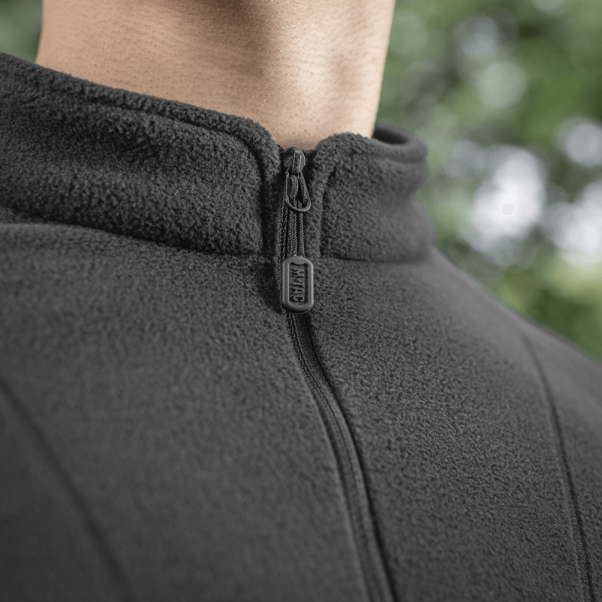 Lähikuva M-Tac Delta Polartec Raglan -takista mustassa fleecessä, vetoketju ja korkea kaulus, sopiva ulkoiluun ja suojaksi kylmältä.