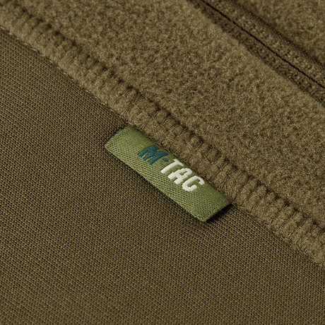 Merkintä M-Tac Polartec Sport -hupparissa oliivinvihreänä, painotus lämmöneristyksessä ja kosteuden siirrossa.