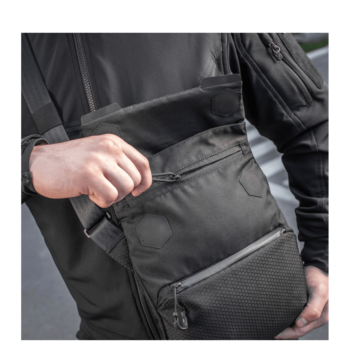 Mies kantaa M-Tac Konvert Taske Eliteä, valmistettu kestävästä Cordura-materiaalista, magnetlukning ja säädettävä olkahihna.