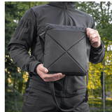 Mies pitää M-Tac Konvert Taske Eliteä mustana, valmistettu Cordura-materiaalista, säädettävä olkahihna ja tablet-design.