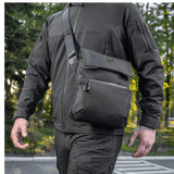 Mies kantaa M-Tac Konvert Taske Eliteä Cordura-materiaalista, säädettävä olkahihna ja tablet-design, ulkokuvassa.