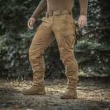 Mies ulkona pukeutuneena M-Tac Aggressor Gen.II Vintage -housuihin, korostaen kestävyyttä ja tyyliä peltoon ja arkeen.