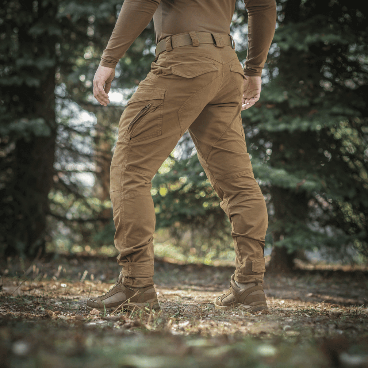 Henkilö metsässä pukeutuneena M-Tac Aggressor Gen.II Vintage -housuihin vintage-viimeistelyllä, sopivat peltoon ja arkeen.